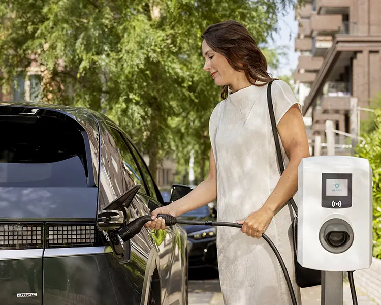 Une femme branche sa voiture à une borne de recharge